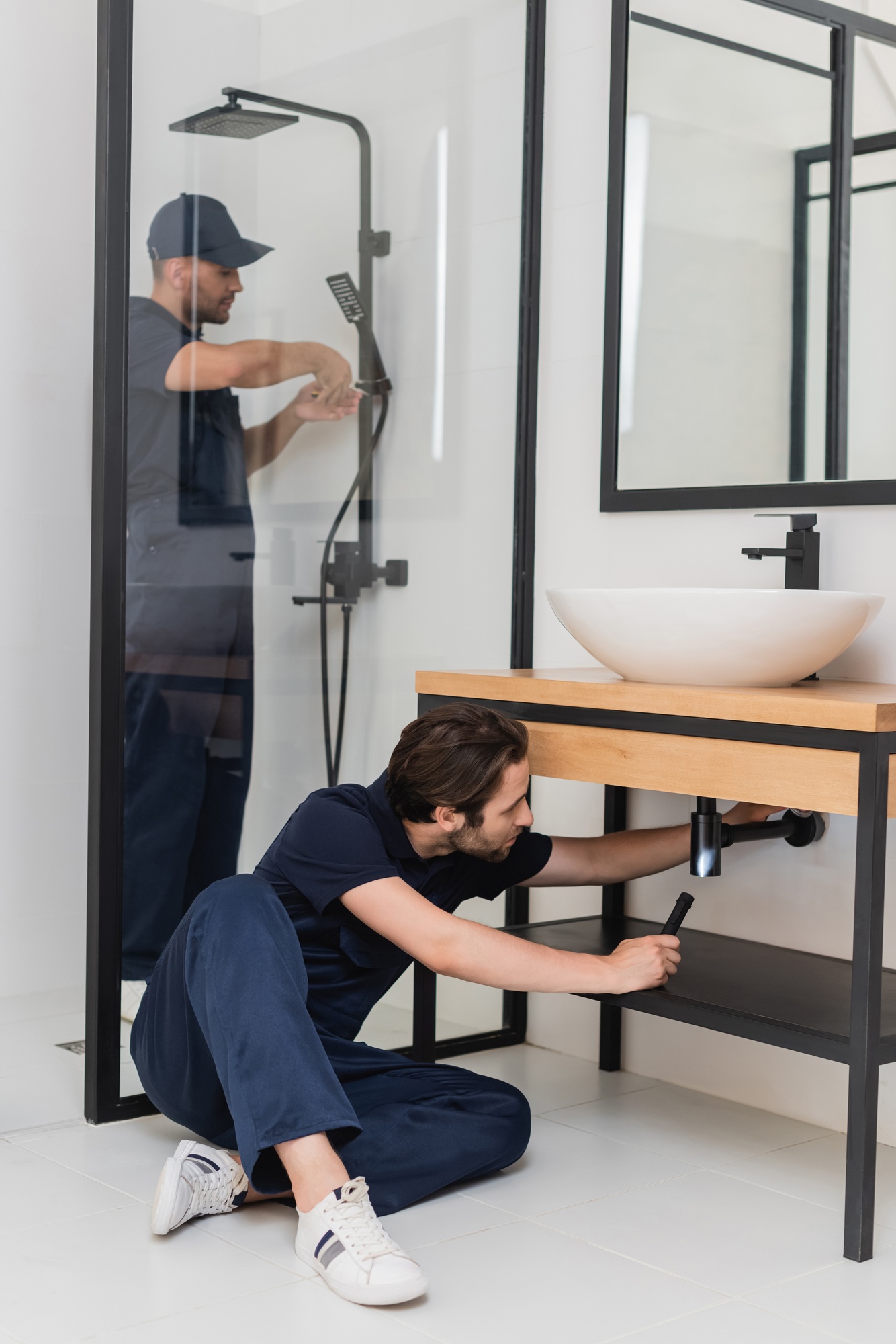 plumbers in uniform working together in bathroom